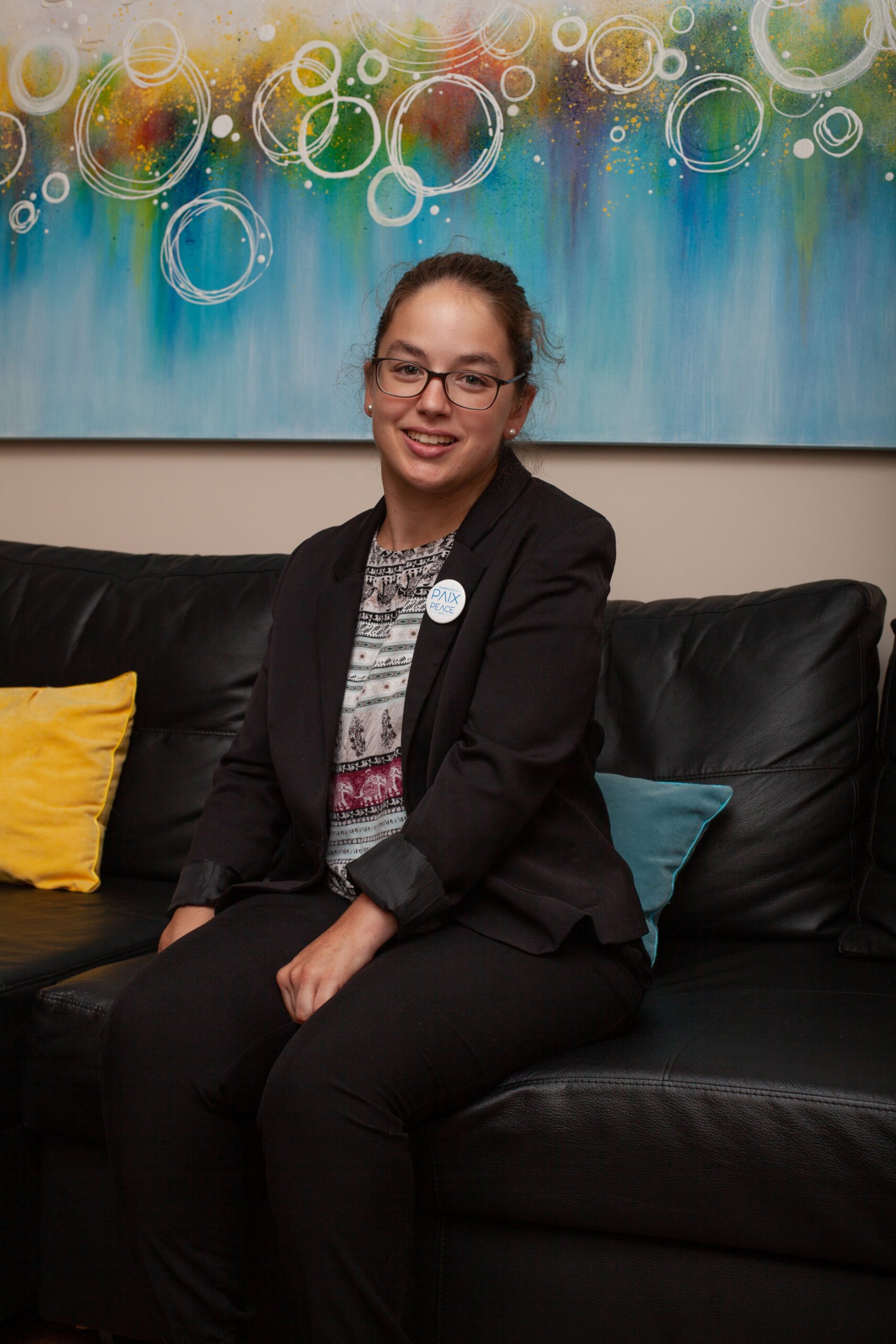 A woman sitting on a couch wearing a black blazer
