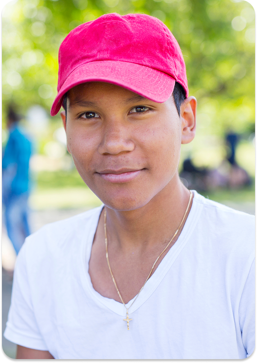 a boy wearing a pink cap in a park